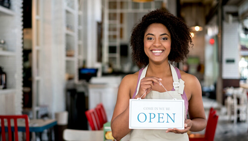Smiling female business owner holding an open sign at a restaraunt